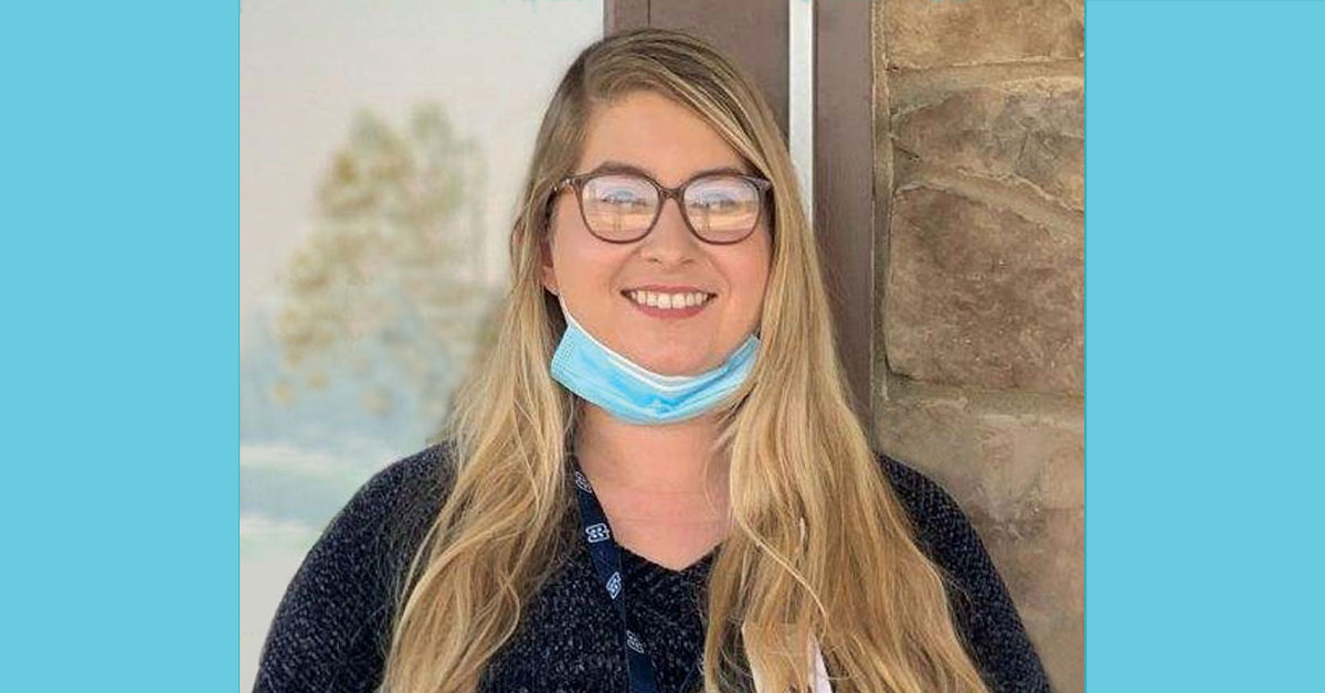 Smiling young woman with a medical mask pulled down around her neck. 